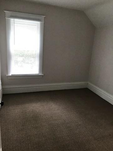 bonus room with dark colored carpet, vaulted ceiling, and baseboards