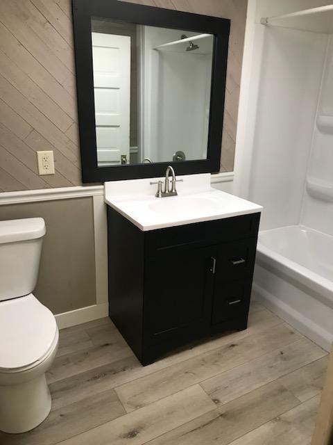full bathroom featuring wood finished floors, toilet, vanity, and  shower combination