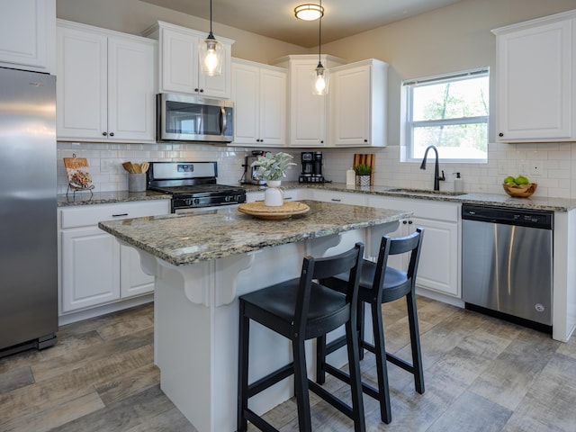 59376 Silvergrass Ave, Mattawan, MI 49071 - kitchen with stainless steel appliances, a sink, white cabinets, and a kitchen breakfast bar