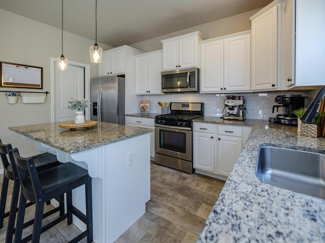 59376 Silvergrass Ave, Mattawan, MI 49071 - kitchen featuring appliances with stainless steel finishes, a center island, white cabinetry, a kitchen bar, and tasteful backsplash