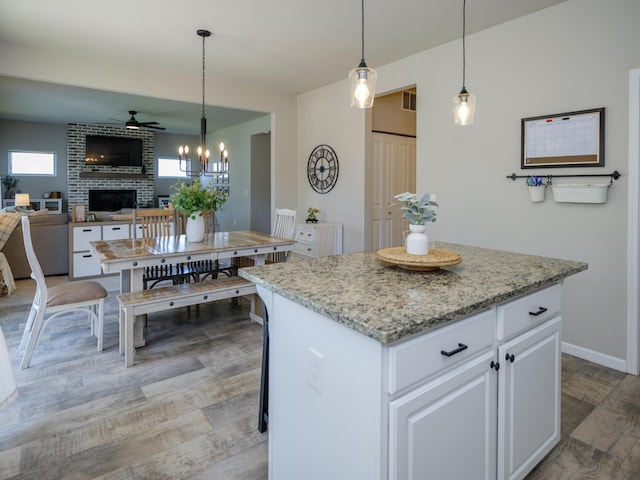 59376 Silvergrass Ave, Mattawan, MI 49071 - kitchen featuring ceiling fan, a fireplace, white cabinets, decorative light fixtures, and a chandelier