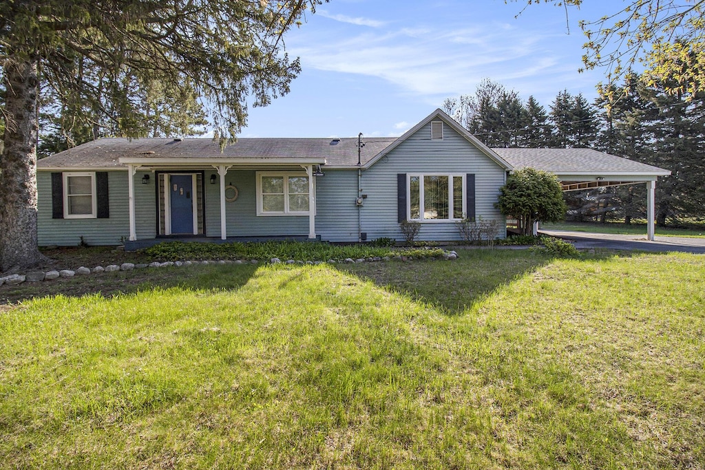 1234 N Jebavy Dr, Ludington, MI 49431 - ranch-style house with a porch, a carport, a front lawn, and roof with shingles