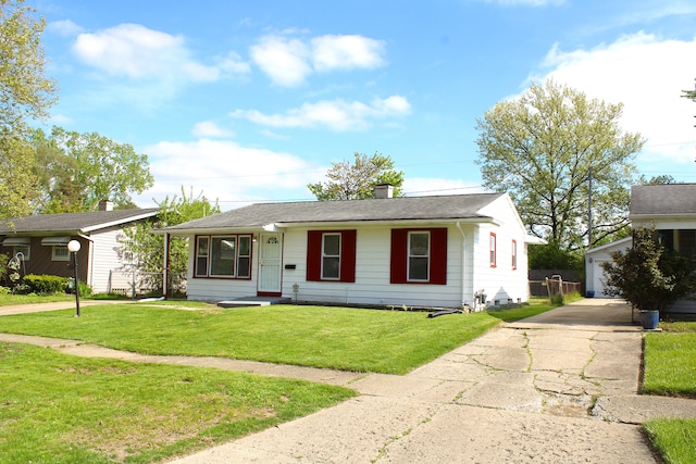 ranch-style home featuring an outbuilding, a front lawn, a chimney, and a detached garage
