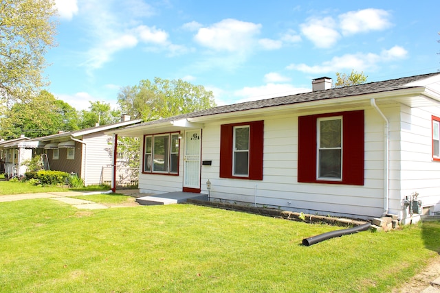 ranch-style home featuring a chimney, a front yard, and a shingled roof