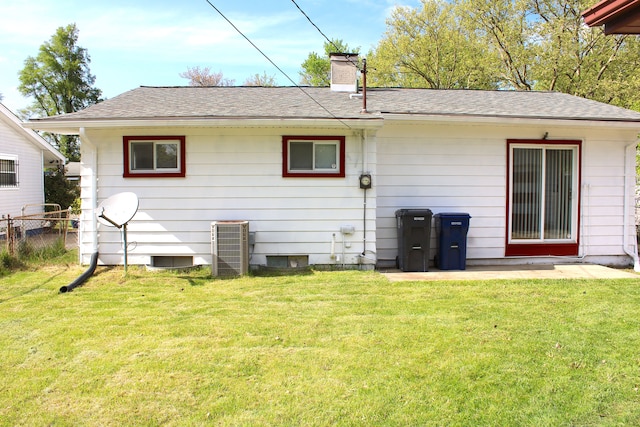 back of house with a chimney and roof with shingles