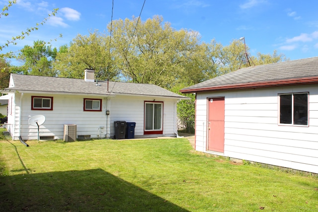 back of house with a lawn, a chimney, and a shingled roof