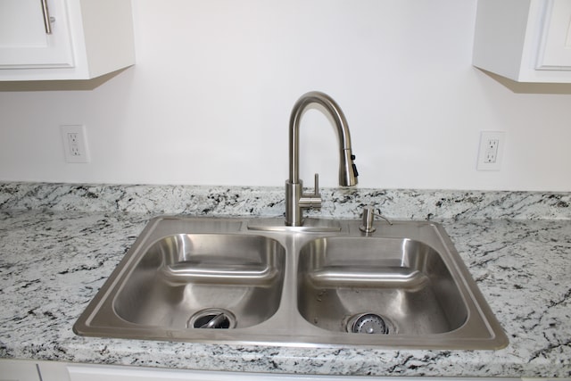 kitchen view of a sink and white cabinetry