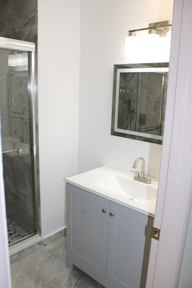 full bathroom featuring a shower stall, vanity, and marble finish floors