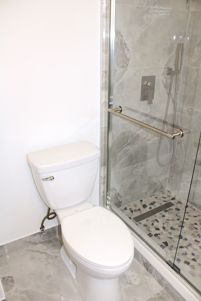 full bath with a stall shower, toilet, and marble finish flooring