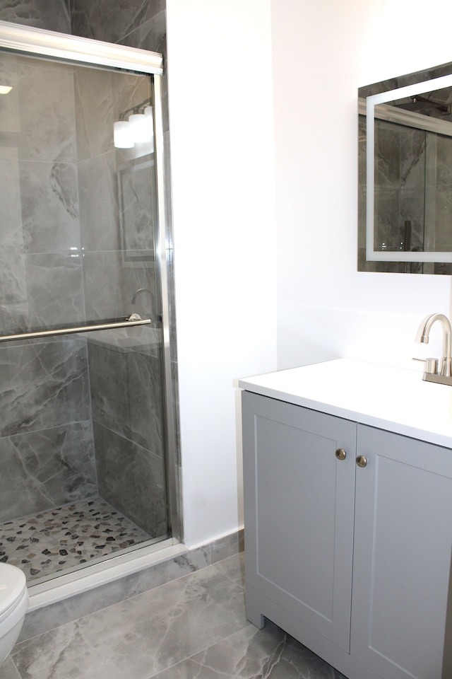 bathroom with toilet, a shower stall, marble finish floors, and vanity