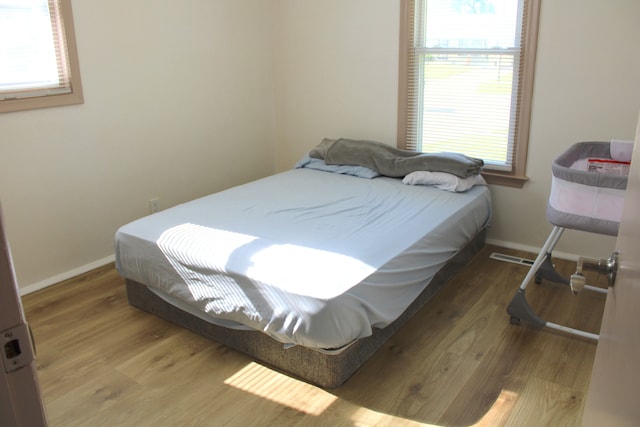 bedroom featuring multiple windows, wood finished floors, and baseboards