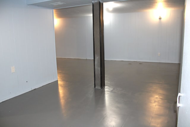 basement featuring baseboards and wooden walls
