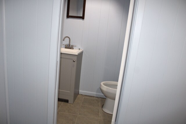 half bathroom with vanity, tile patterned floors, and toilet