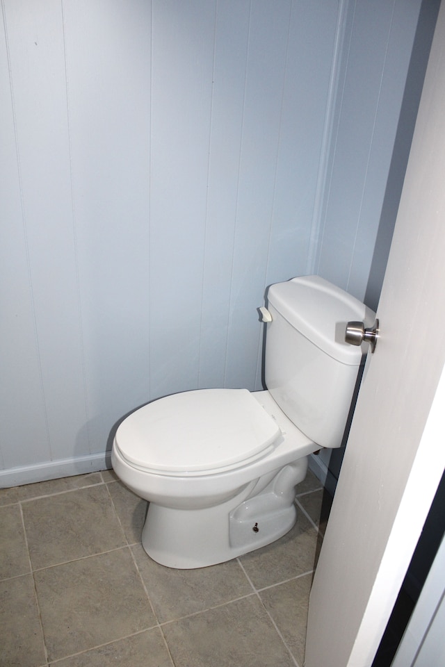 bathroom with toilet, tile patterned floors, and a decorative wall
