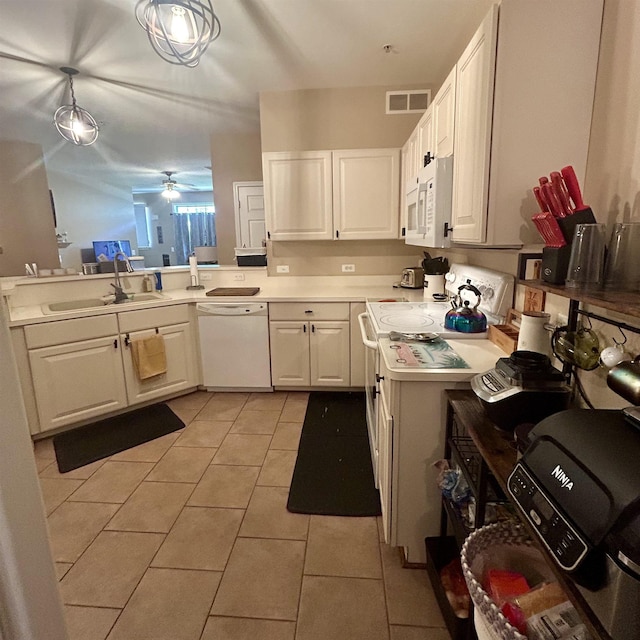 kitchen with white appliances, a sink, light countertops, light tile patterned floors, and white cabinetry