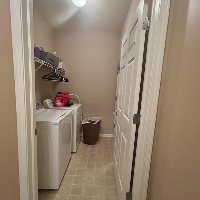 laundry area featuring washing machine and clothes dryer, light tile patterned floors, and baseboards