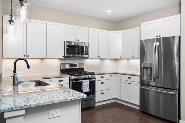 611 Woodland Dr, Dexter, MI 48130 - kitchen with stainless steel appliances, a sink, light stone counters, white cabinets, and hanging light fixtures