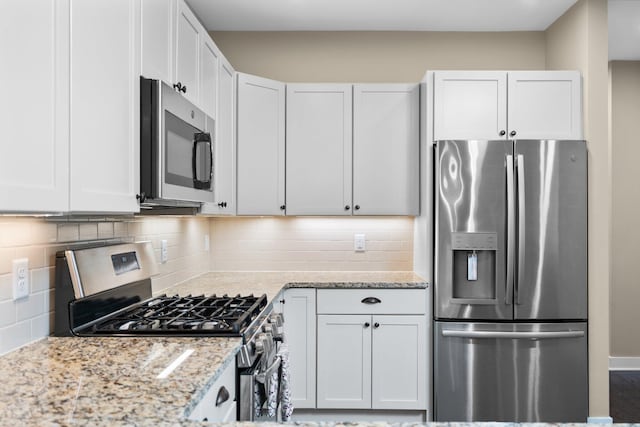 611 Woodland Dr, Dexter, MI 48130 - kitchen featuring stainless steel appliances, light stone counters, white cabinets, and decorative backsplash