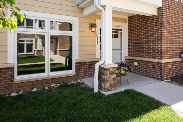 611 Woodland Dr, Dexter, MI 48130 - view of exterior entry with brick siding, a porch, and a lawn
