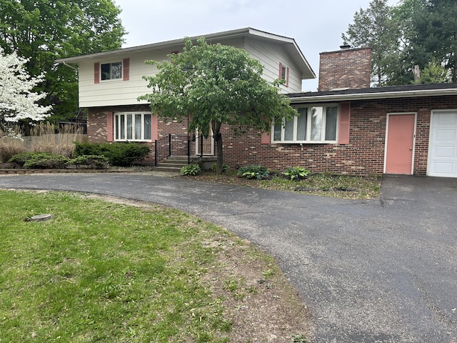 29 Douglas Ave, Coldwater, MI 49036 - view of front of house with brick siding, a chimney, driveway, and an attached garage