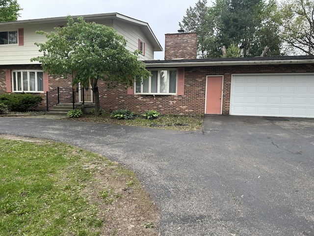 29 Douglas Ave, Coldwater, MI 49036 - view of front of property featuring asphalt driveway, brick siding, a chimney, and an attached garage
