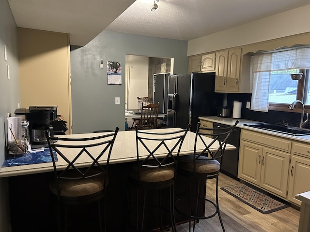 29 Douglas Ave, Coldwater, MI 49036 - kitchen featuring a sink, black appliances, a breakfast bar, and light wood-type flooring