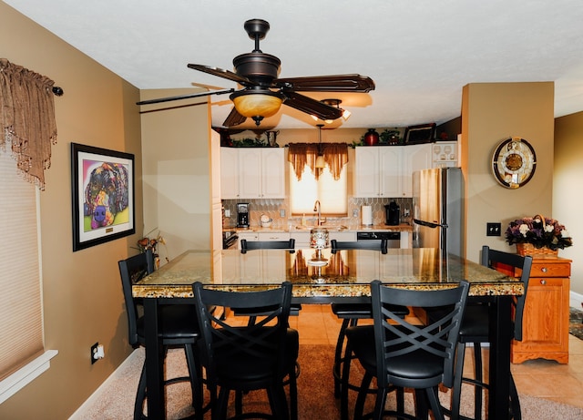 kitchen featuring stainless steel appliances, a ceiling fan, a breakfast bar area, and white cabinetry