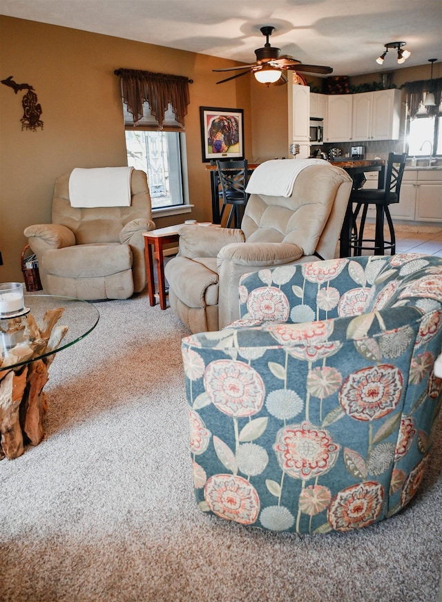 living area with a ceiling fan and light carpet