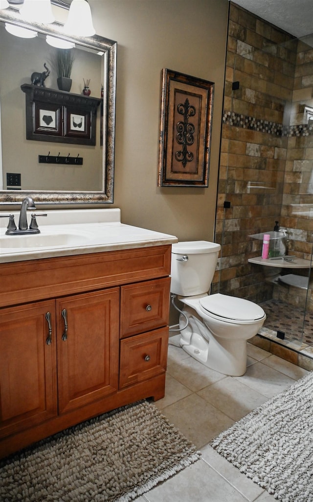 full bath with toilet, tiled shower, tile patterned flooring, and vanity