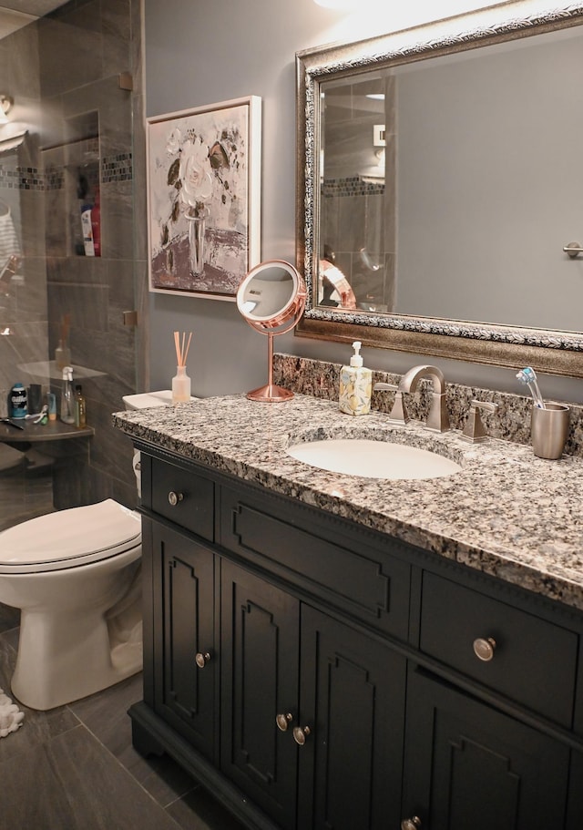 bathroom with a shower stall, vanity, and toilet