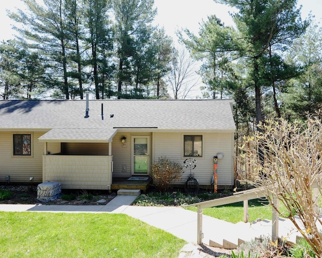 ranch-style house featuring roof with shingles and a front yard