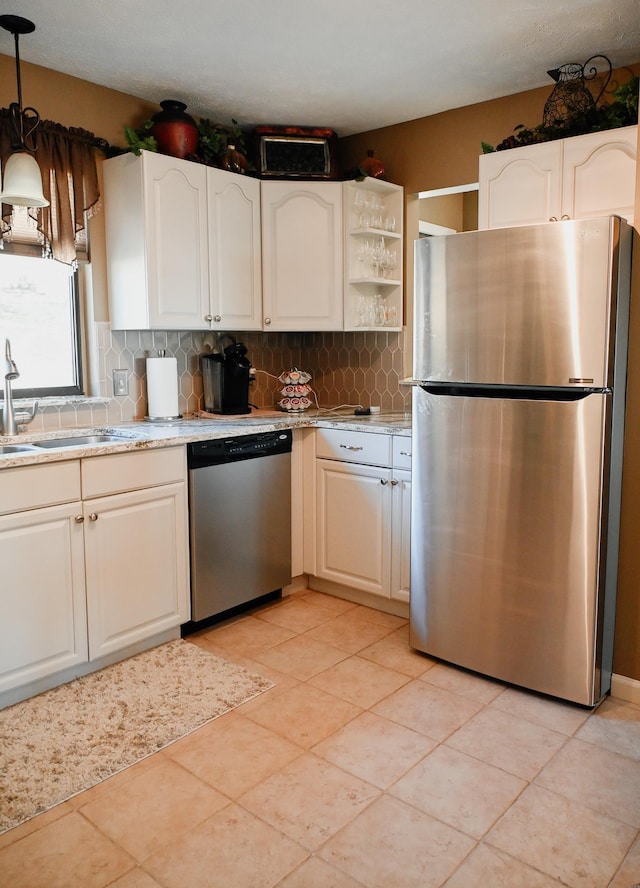 kitchen featuring appliances with stainless steel finishes, a sink, backsplash, and hanging light fixtures