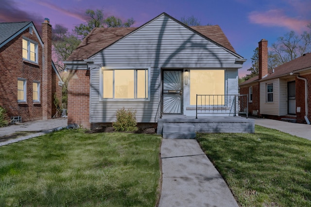 bungalow-style home with a lawn and roof with shingles