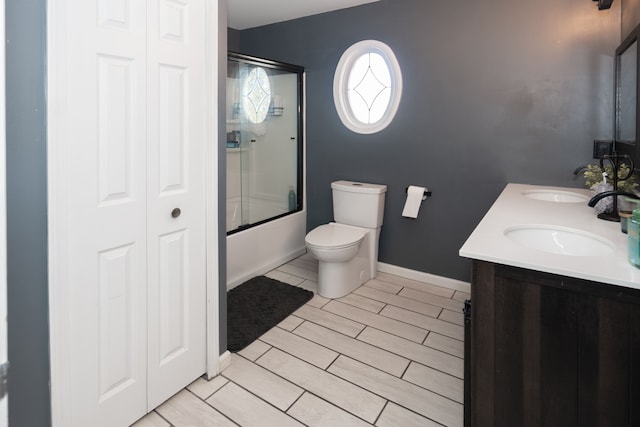 472 Central St, Marysville, MI 48040 - bathroom featuring toilet, shower / bath combination with glass door, baseboards, double vanity, and a closet