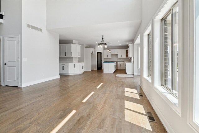 19266 Thompson Dr, Macomb, MI 48042 - unfurnished living room featuring a chandelier, light wood-style floors, baseboards, recessed lighting, and a high ceiling