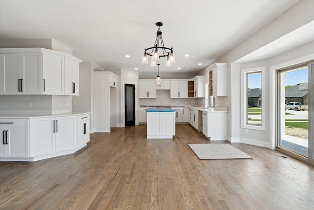 19266 Thompson Dr, Macomb, MI 48042 - kitchen with open shelves, a center island, a sink, wood finished floors, and a chandelier