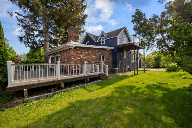 back of house with a lawn, a chimney, a deck, brick siding, and central air condition unit