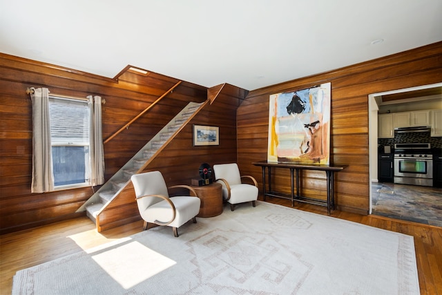 sitting room featuring hardwood / wood-style flooring, stairs, and wooden walls