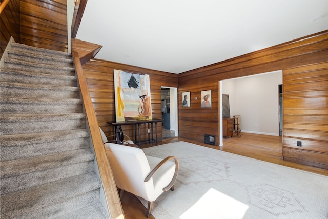 stairway featuring wooden walls, wood finished floors, and baseboards