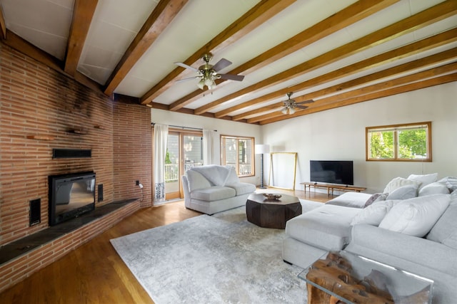 living area featuring a ceiling fan, wood finished floors, beam ceiling, and a fireplace