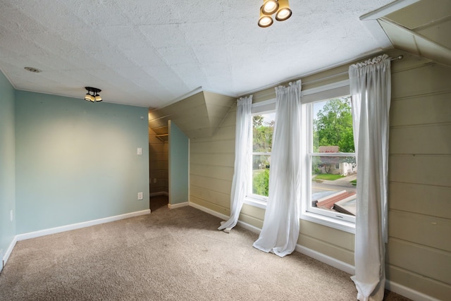 spare room featuring carpet floors, vaulted ceiling, and baseboards