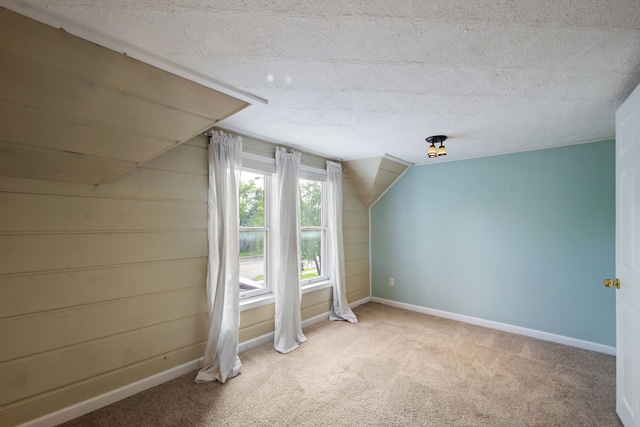 additional living space featuring light colored carpet, baseboards, and vaulted ceiling