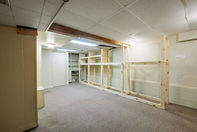 finished basement featuring a drop ceiling, carpet floors, and baseboards