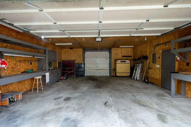 garage with a workshop area, electric panel, and a garage door opener
