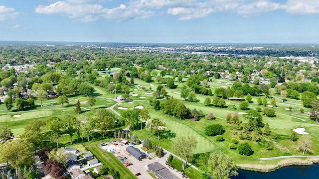 aerial view of property and surrounding area with a local golf course, a nearby body of water, and a tree filled landscape