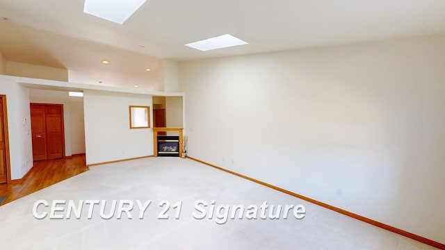 5966 Red Feather Dr, Bay City, MI 48706 - unfurnished living room featuring a skylight, a glass covered fireplace, carpet floors, and baseboards