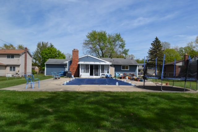 5448 Fairview Dr, Grand Blanc, MI 48439 - rear view of house featuring a trampoline, a patio, a yard, and a chimney