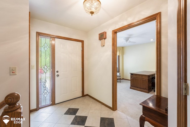 entryway featuring baseboards, light tile patterned floors, ceiling fan, and light carpet