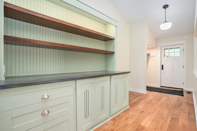 foyer entrance with light wood-style flooring, baseboards, and lofted ceiling