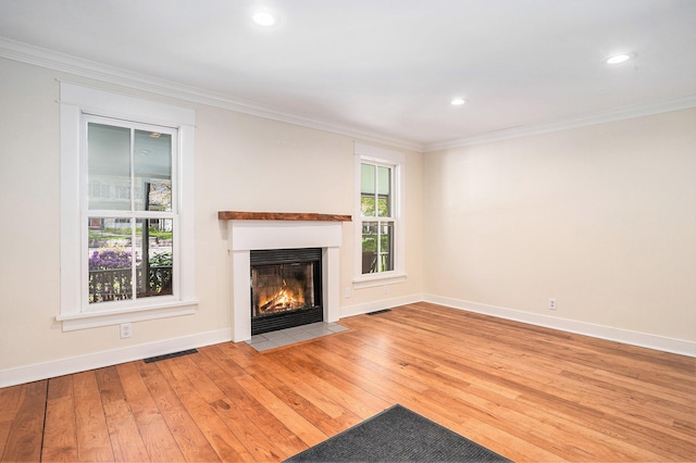 unfurnished living room with a fireplace with flush hearth, hardwood / wood-style flooring, ornamental molding, baseboards, and recessed lighting
